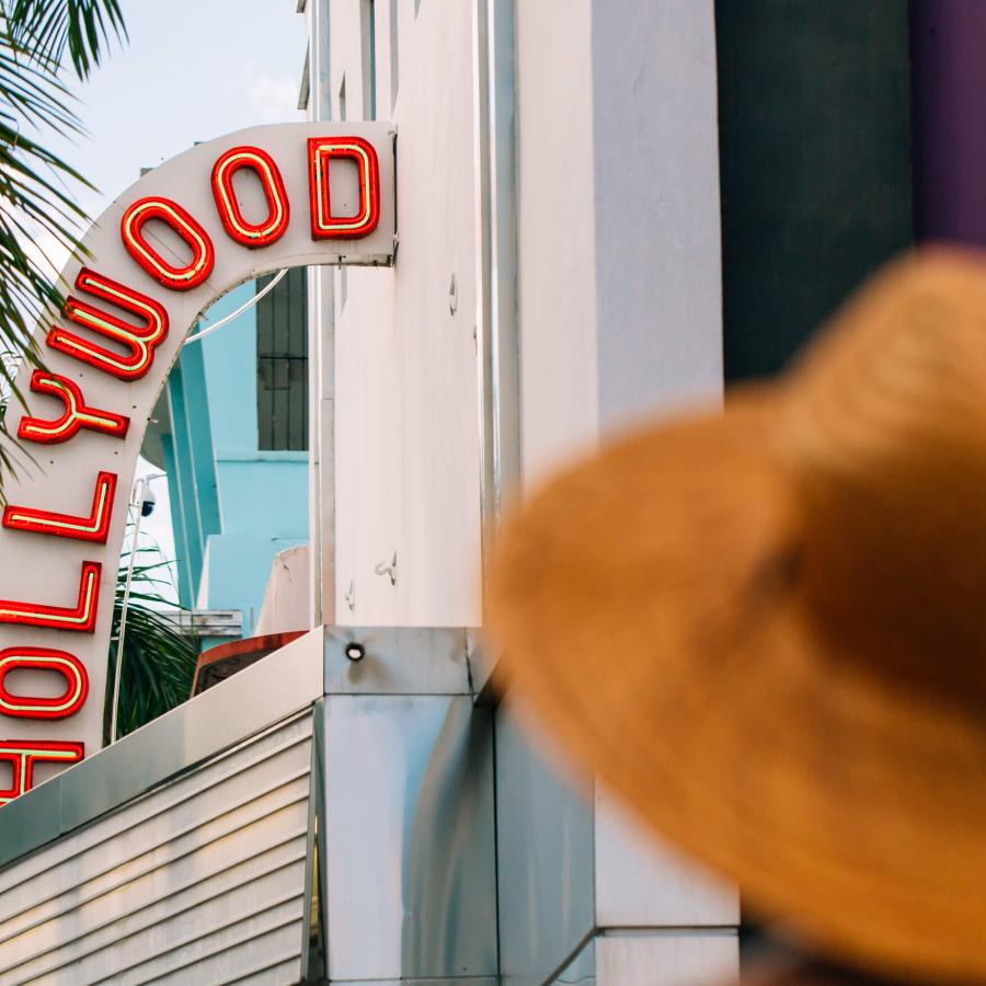 Woman in a hat standing outside the historic Hollywood Theater in Coamo. 