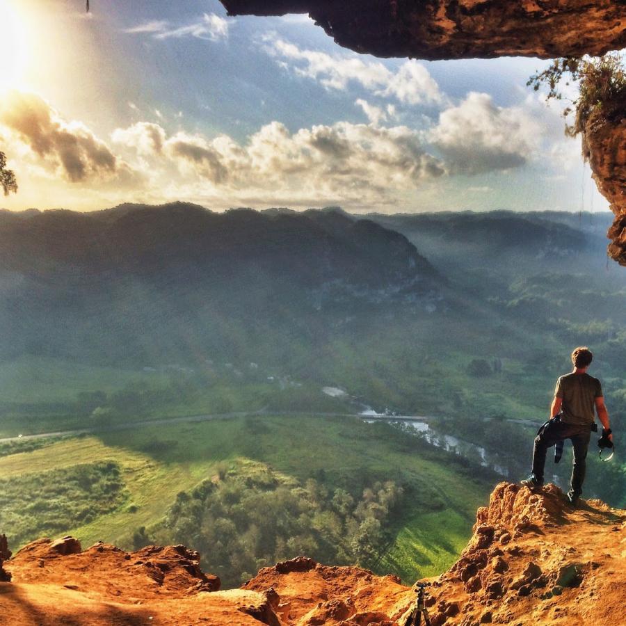 A hiker stands at the mouth of Cueva Ventana.