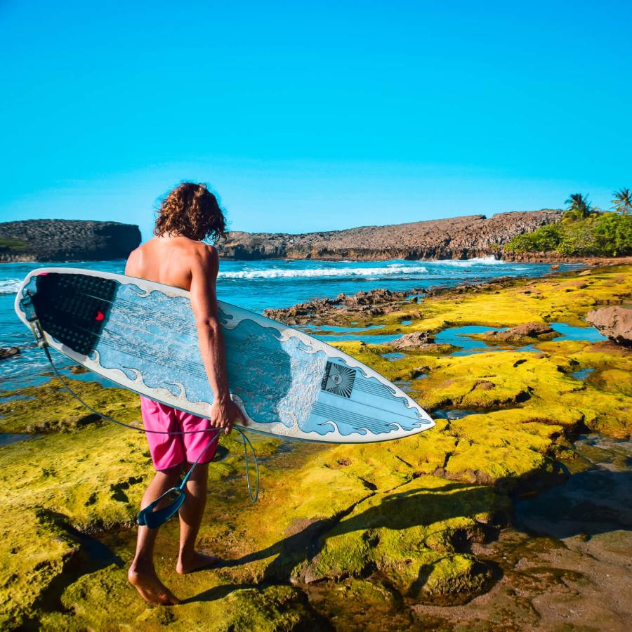 Un surfista camina por los impresionantes acantilados de la Cueva del Indio en Arecibo.