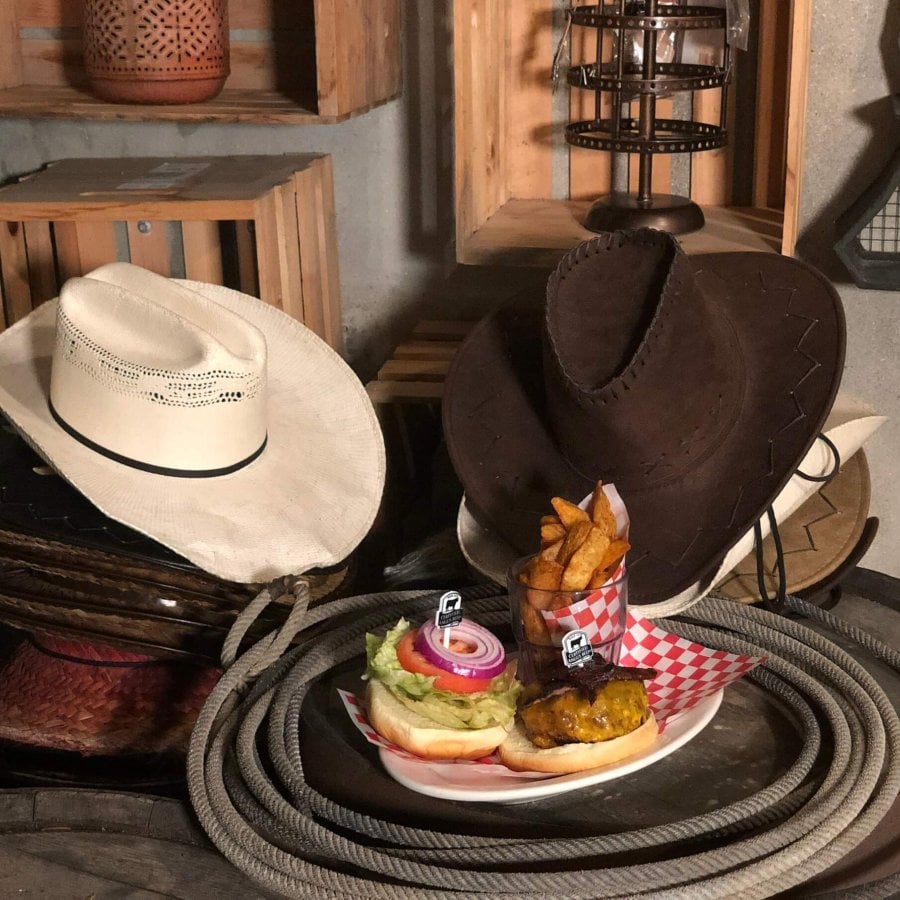 Two cowboy hats and western decorations surround a burger and fries.