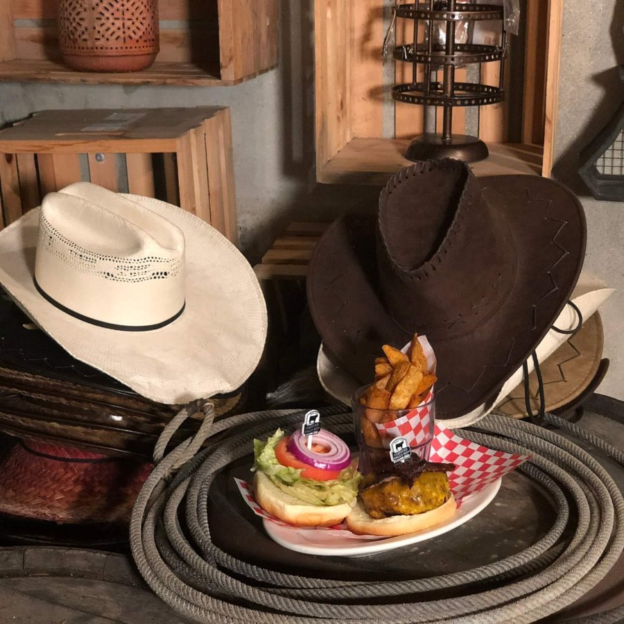 Two cowboy hats and western decorations surround a burger and fries. 