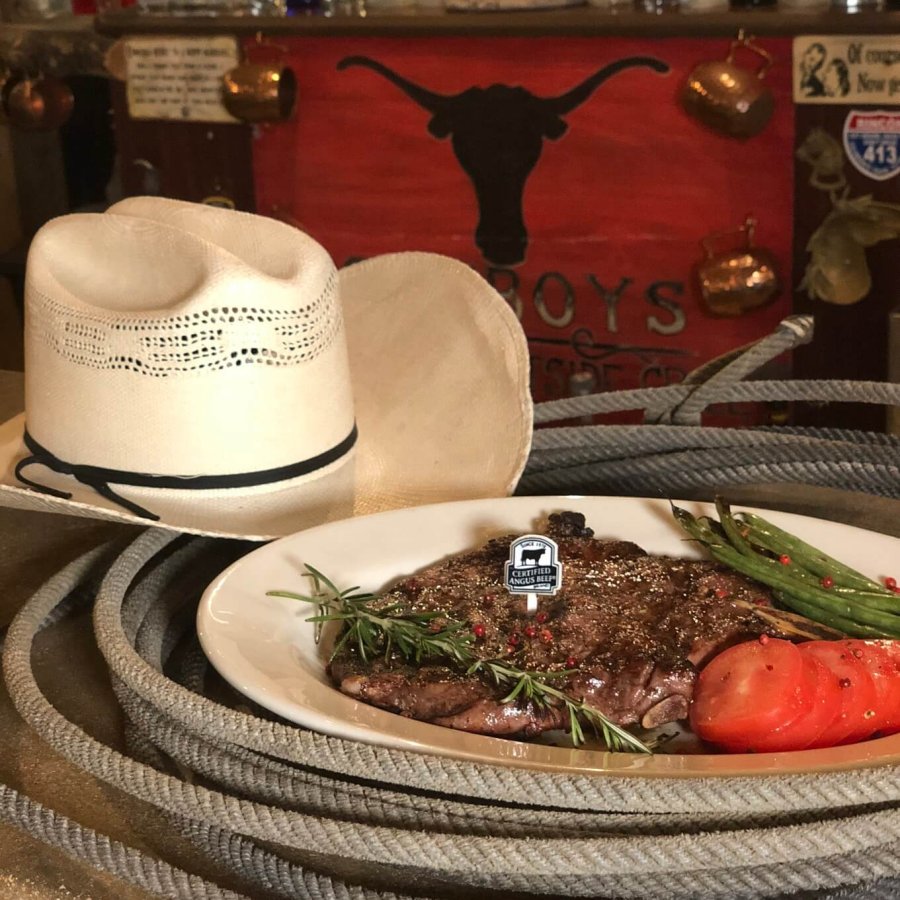 A white cowboy hat beside a steak dinner.