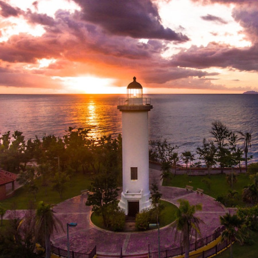 The sun sets behind a lighthouse in Rincón.