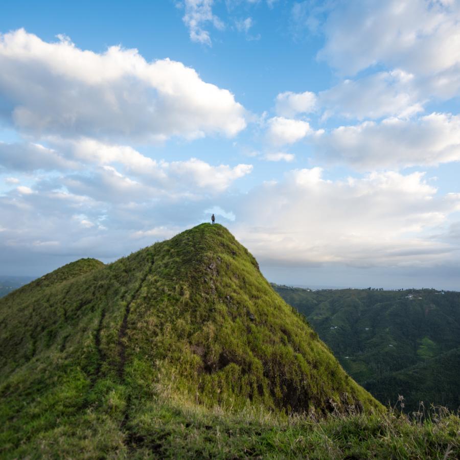A person stands at the peak of mountain in the central region of puerto rico.