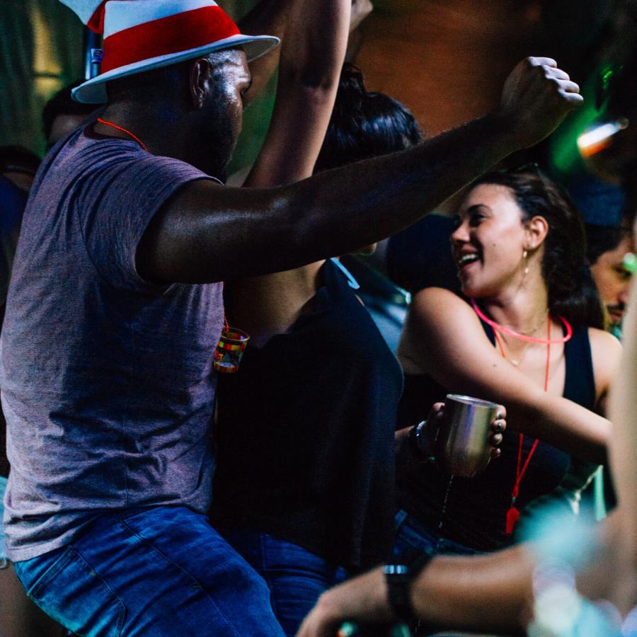 A man in a striped hat dancing in a group. 