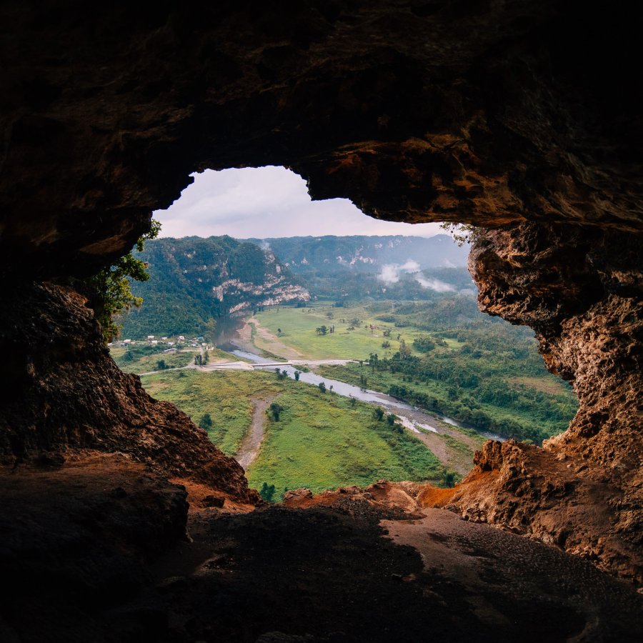 A cave opening reveals a green valley at Cueva Ventana.