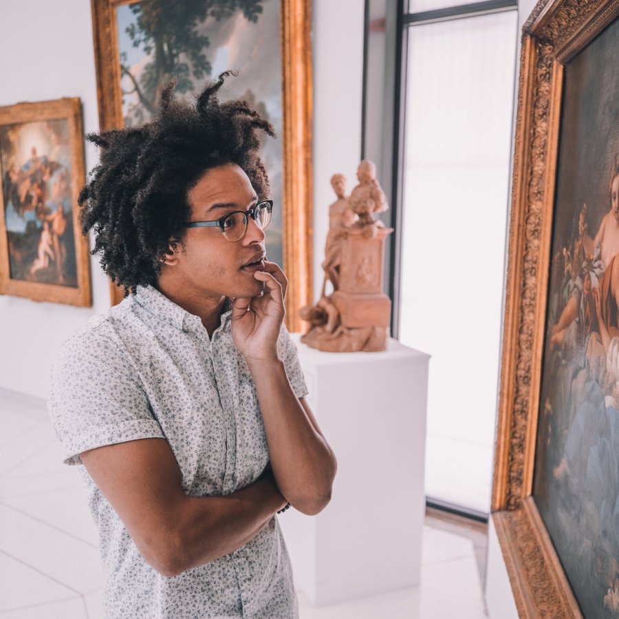A man admires a historic painting hanging in a museum