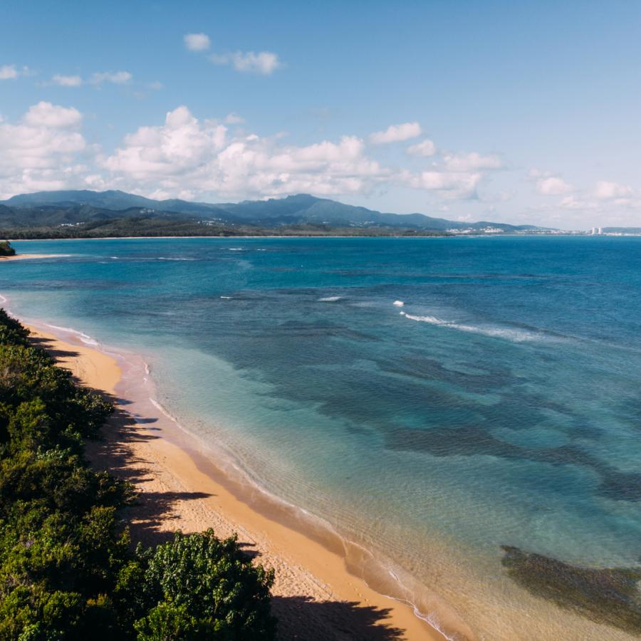 an aerial view of the golden sand and bright blue water of escondida beach in fajardo