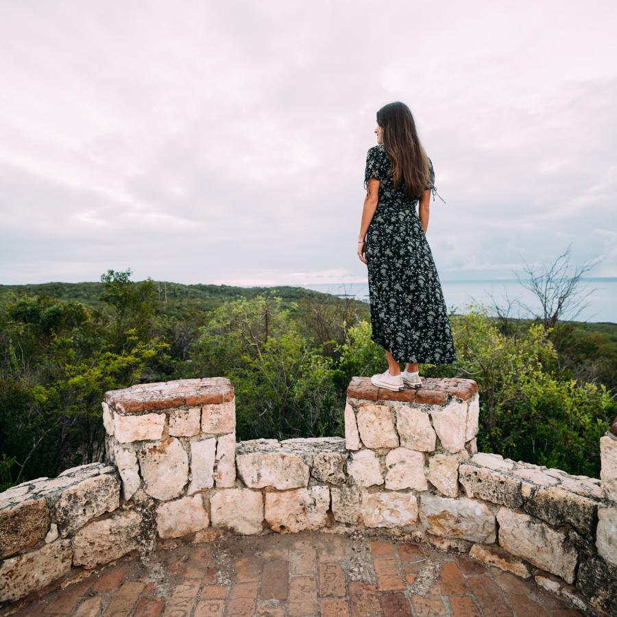 A woman peers over Guánica Dry Forest from the top of Fuerte Capron.
