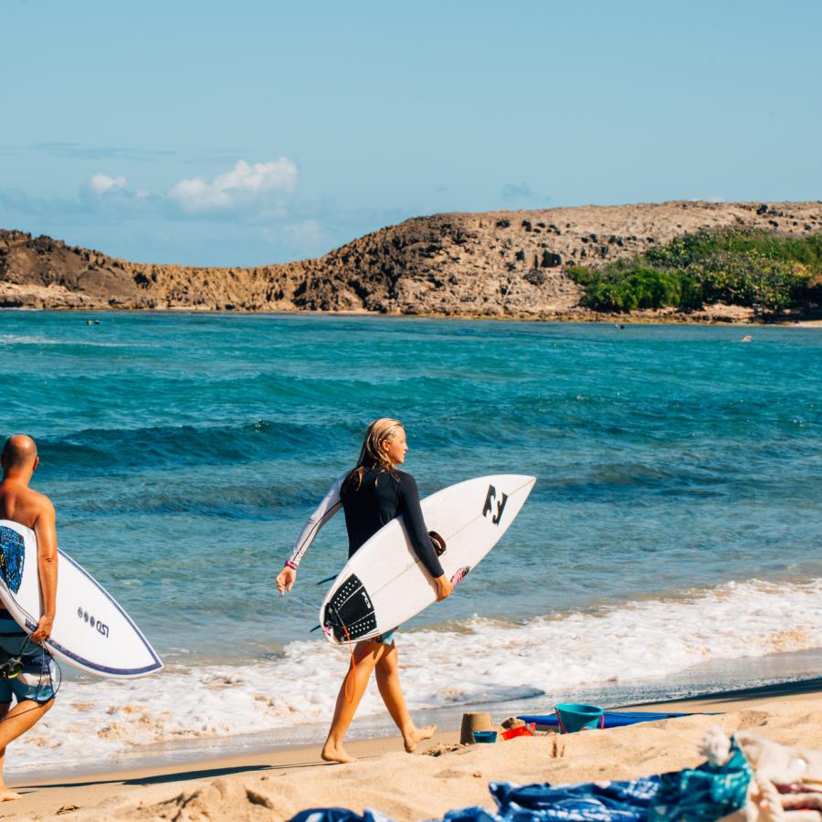 Two surfers stroll along Jobos Beach in Isabela, Puerto Rico.