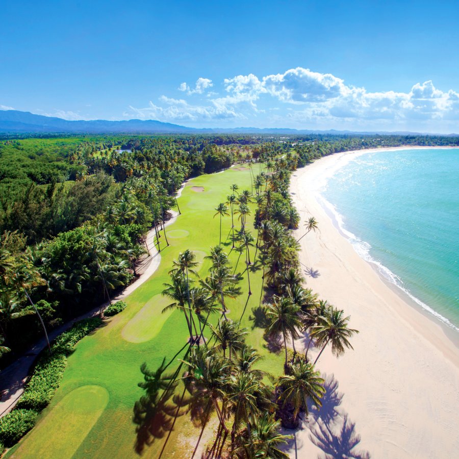 An aerial view of the St. Regis Bahia Beach golf course, nestled between the ocean and the mountains.