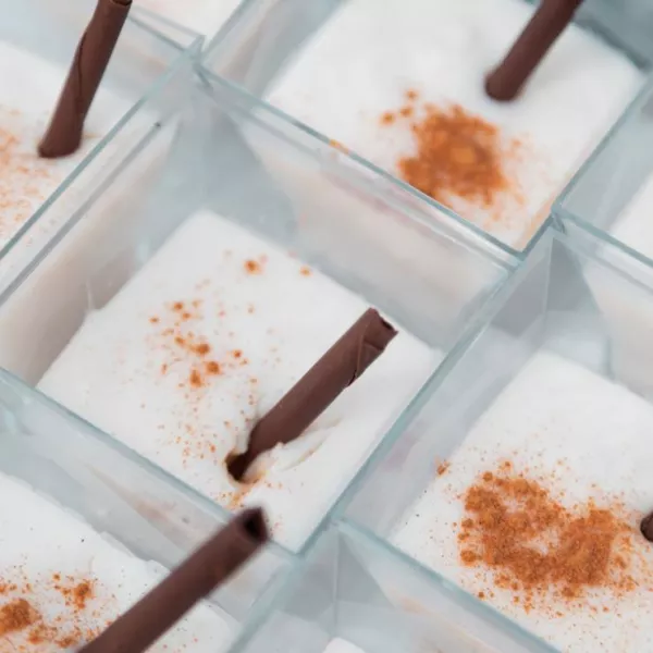 Cups of tembleque, a traditional Puerto Rican coconut dessert, garnished with cinnamon sticks.