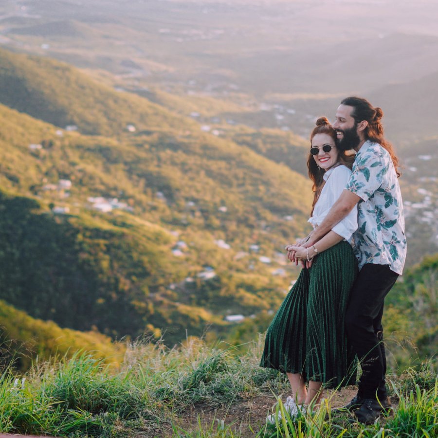 Una pareja se abraza sobre un hermoso valle de montañas.