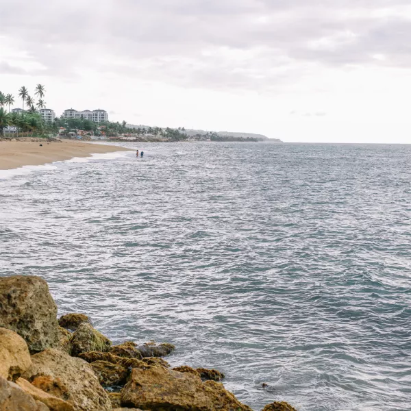 Rocas en primer plano con playa y océano que se extienden hacia atrás en la distancia