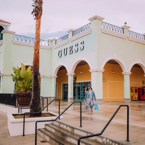 A woman walks away from a store with a bag in hand