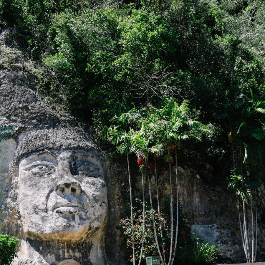 A massive face carved into the side of a steep stone cliff 