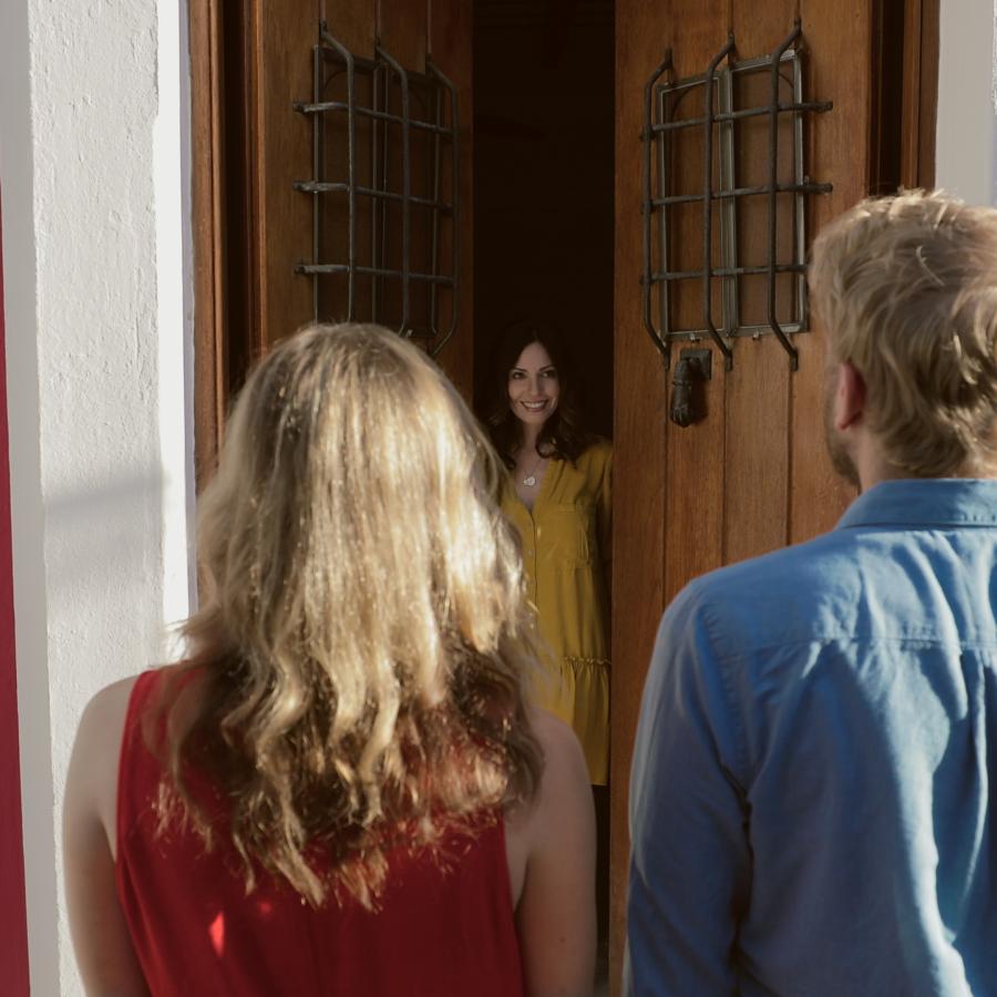 Woman opening a pair of front doors to visitors