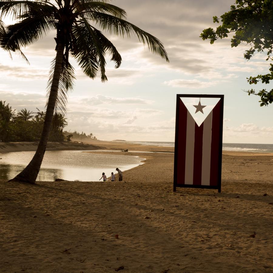A sculpture of the Puerto Rican flag stands on a beach