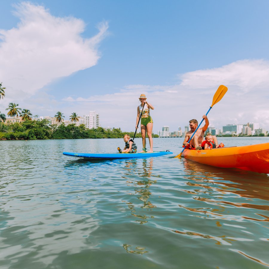 A family of four enjoying their kayak and paddle board at the Condado Lagoon.