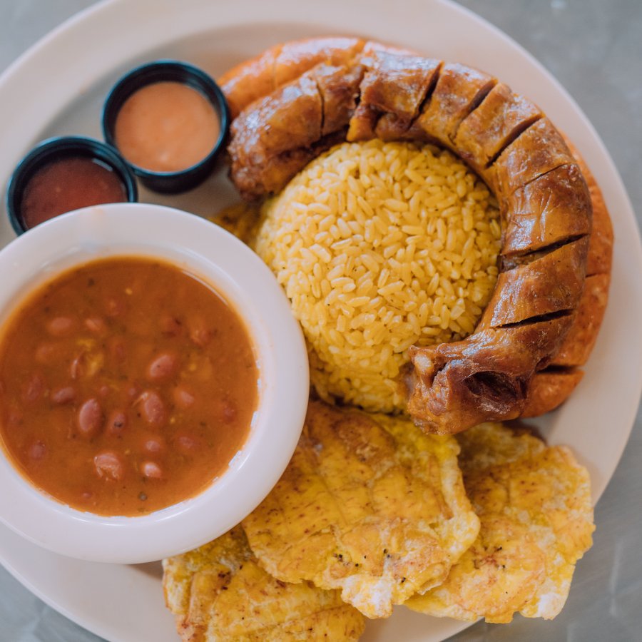 Un plato clásico de longaniza, arroz con habichuelas y tostones.