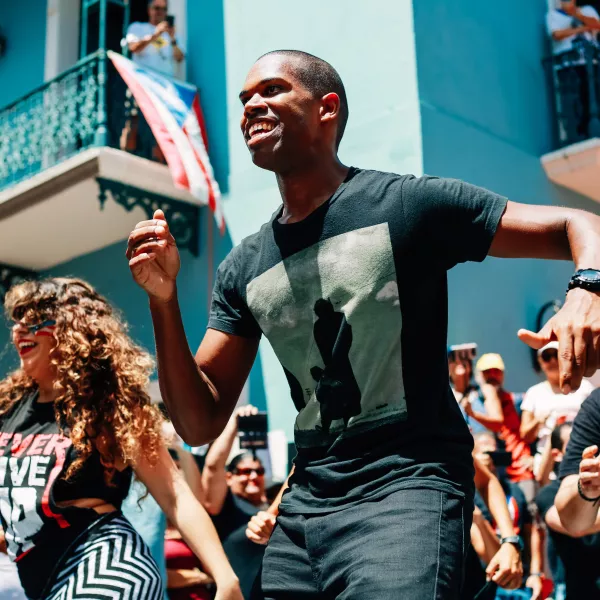 Personas bailando en las calles del Viejo San Juan, celebrando los bailes típicos de Puerto Rico.