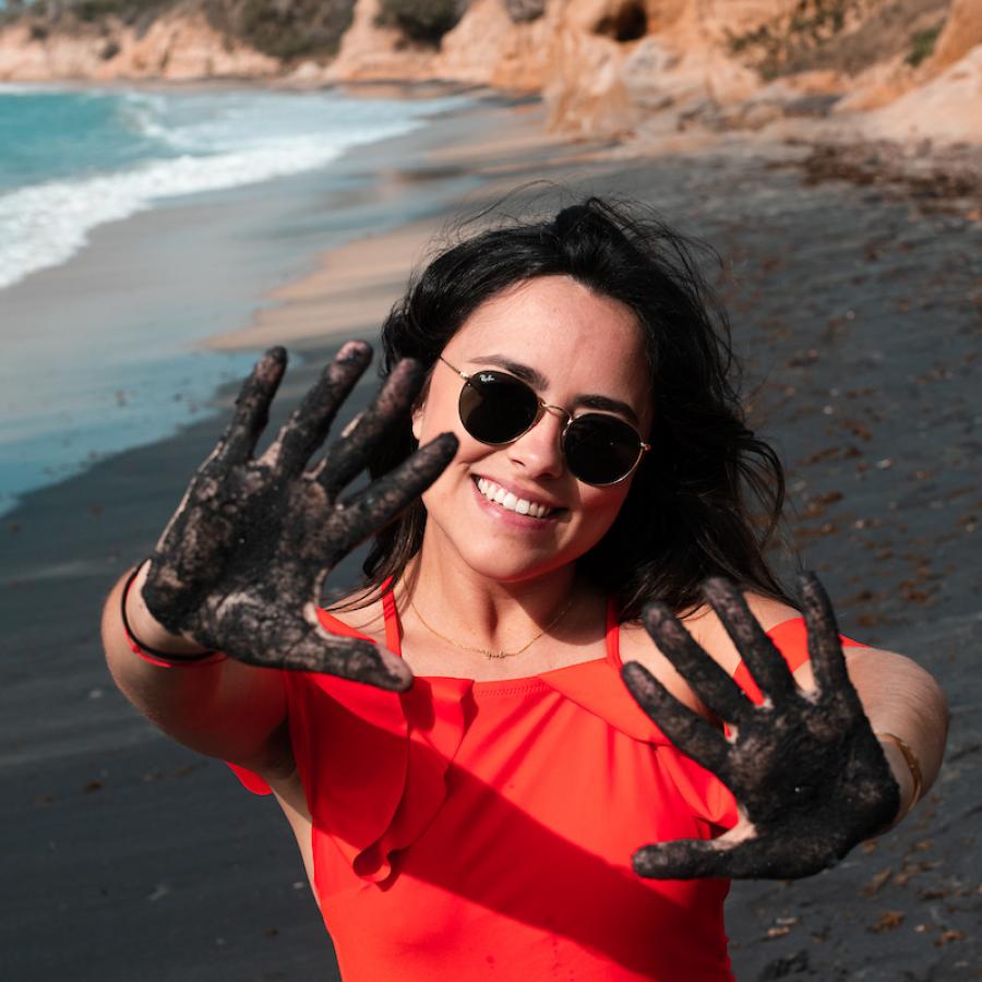 Woman plays with black sand at Playa Negra in Vieques