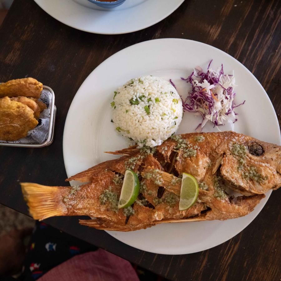 A plate of white rice, fried snapper and tostones. 