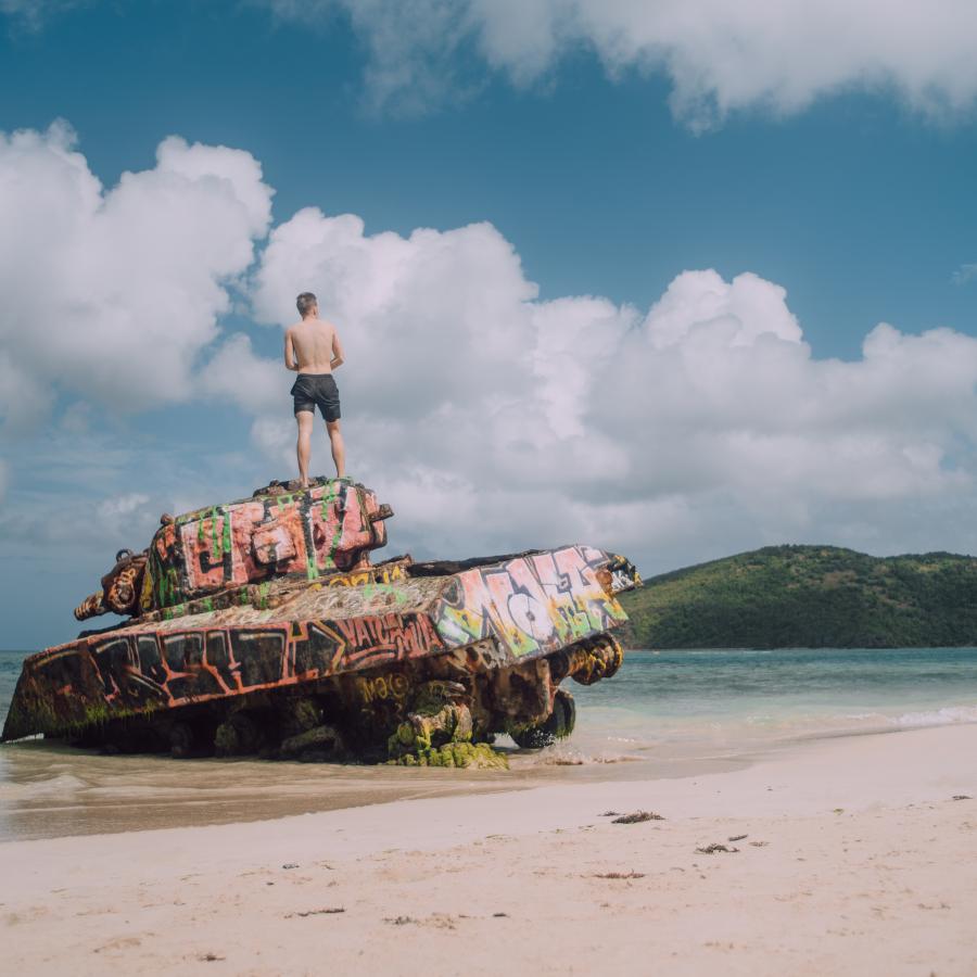 Man standing atop an abandoned Navy tank in the shore of Flamenco Beach in Culebra. 