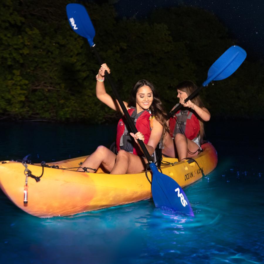 Two women paddling in a kayak during a night at Vieques' bioluminescent bio bay.