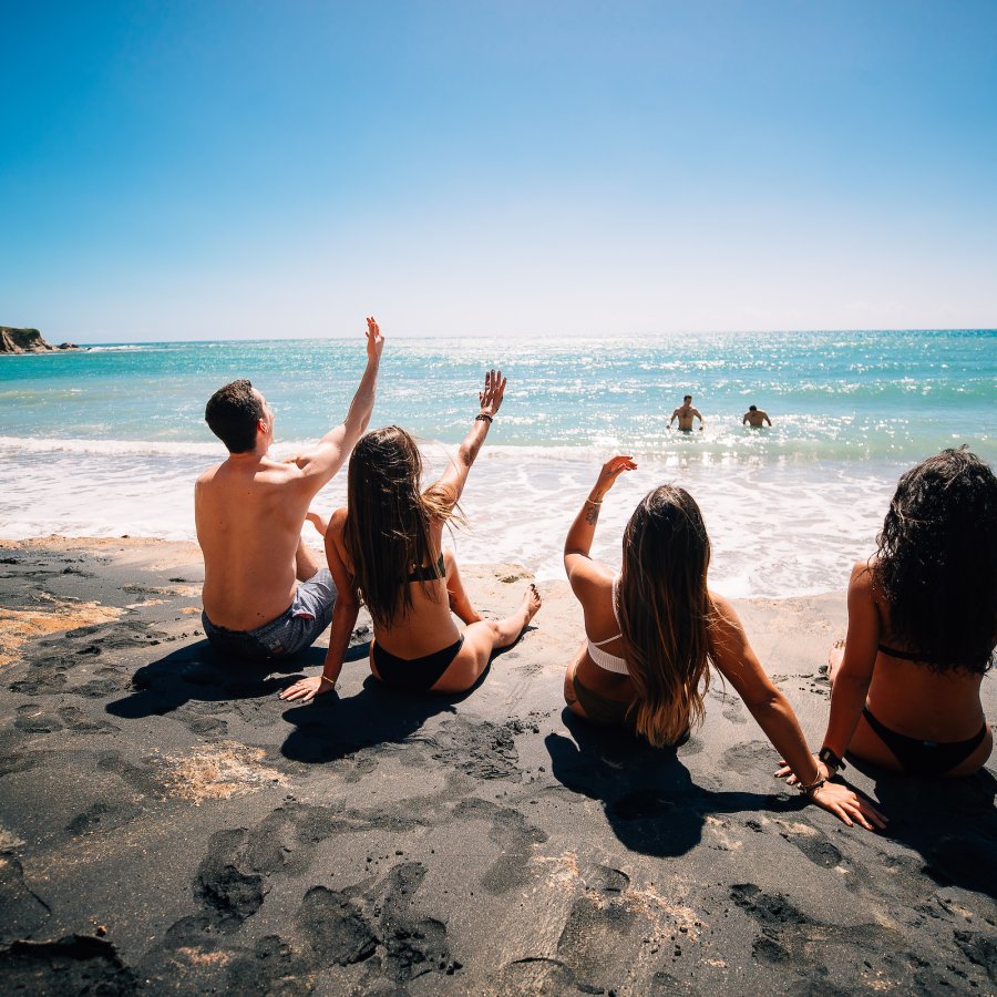 Un grupo de hombres y mujeres disfrutan de las aguas turquesas en la Playa de Arena Negra en Vieques.