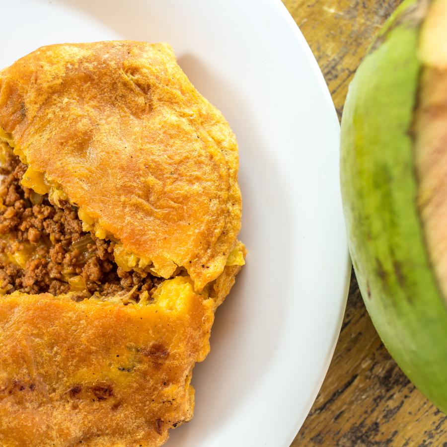 Puerto Rican fritter known as pionono served in a plate with a coconut next to it. 