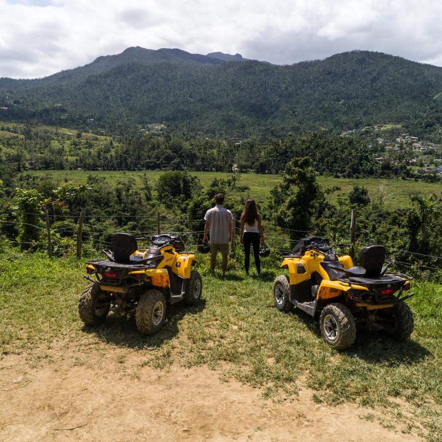 A man and a woman admire the views while resting from their ATV tour, the ATV's are also pictured.