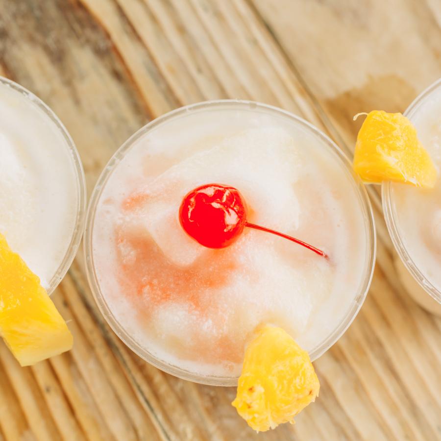 Three piña colada drinks topped with a slice of pineapple and a cherry. 