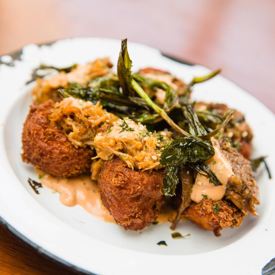 Small plate of Puerto Rican fritters served on a bed of sauce. 