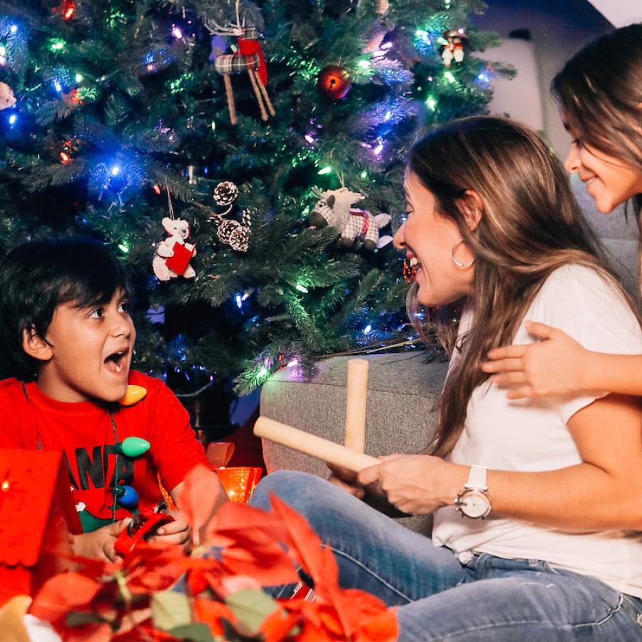 A family sits together by the Christmas tree to play some holiday music.