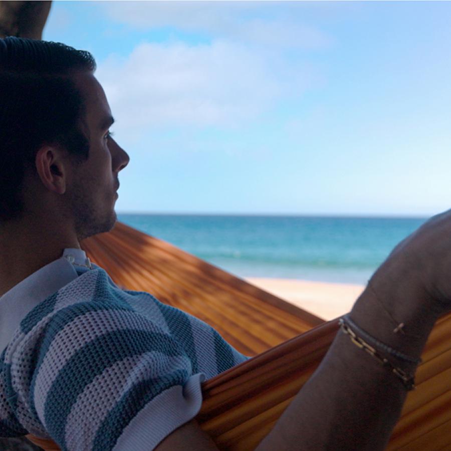 Fashion designer Christian Cowan relaxes in a hammock on a beach in Puerto Rico.