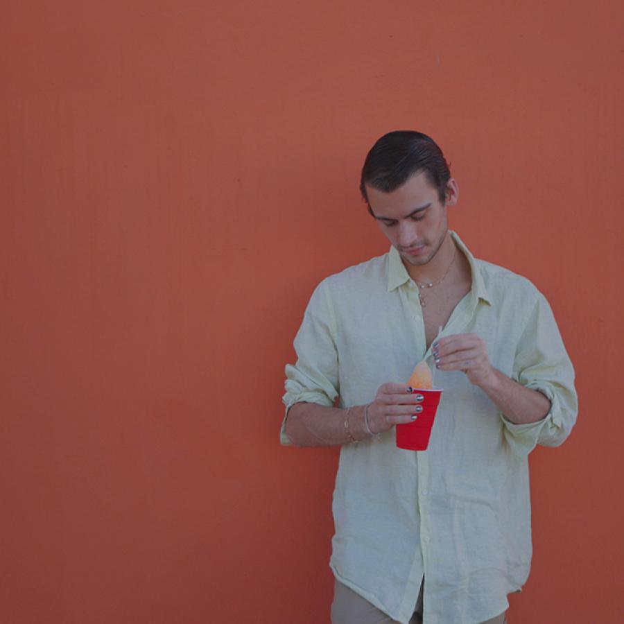 Christian Cowan stands in front of a wall painted orange in Puerto Rico.