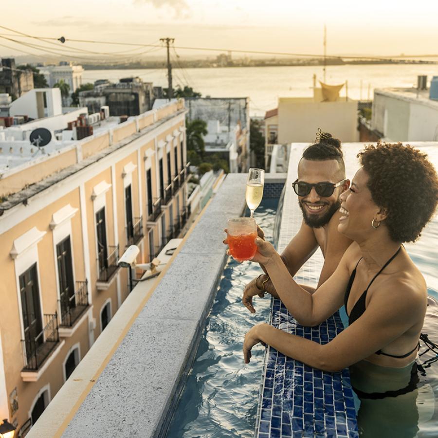 A couple enjoys cocktails in a rooftop pool in Old San Juan