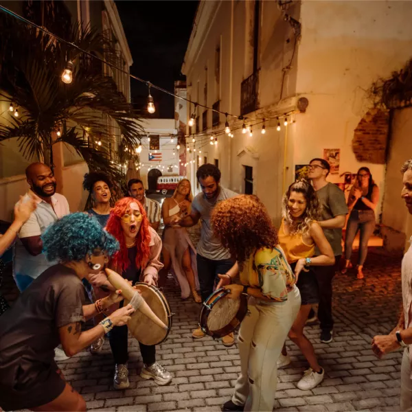 Un grupo de personas baila y toca instrumentos en un callejón de San Juan.