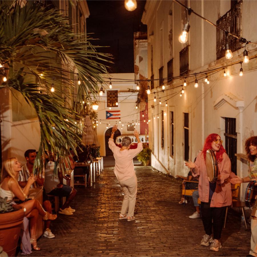 A woman dances on a cobblestone street while a band plays in Old San Juan, Puerto Rico