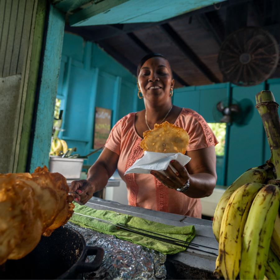 Una mujer sirve un buñuelo recién frito en un quiosco en Pinones, Puerto Rico