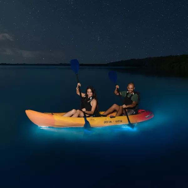 Dos personas navegan en kayak en la bahía bioluminiscente de Laguna Grande.