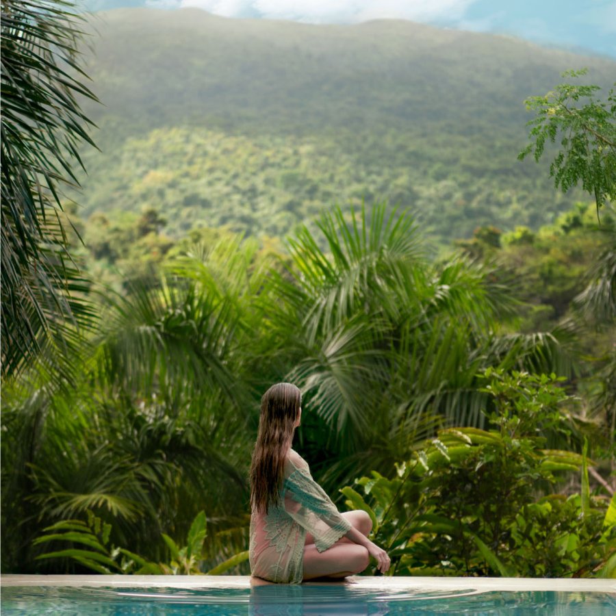 A woman looks over a tropical forest in Puerto Rico.