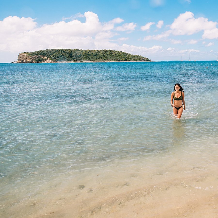 A woman wades through clear, shallow water at Cayo Aurora (AKA Gilligan's Island)