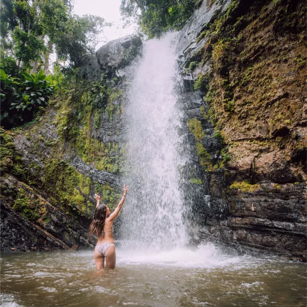 A woman frolics in a waterfall pool at Juan Diego Falls in El Yunque National Forest