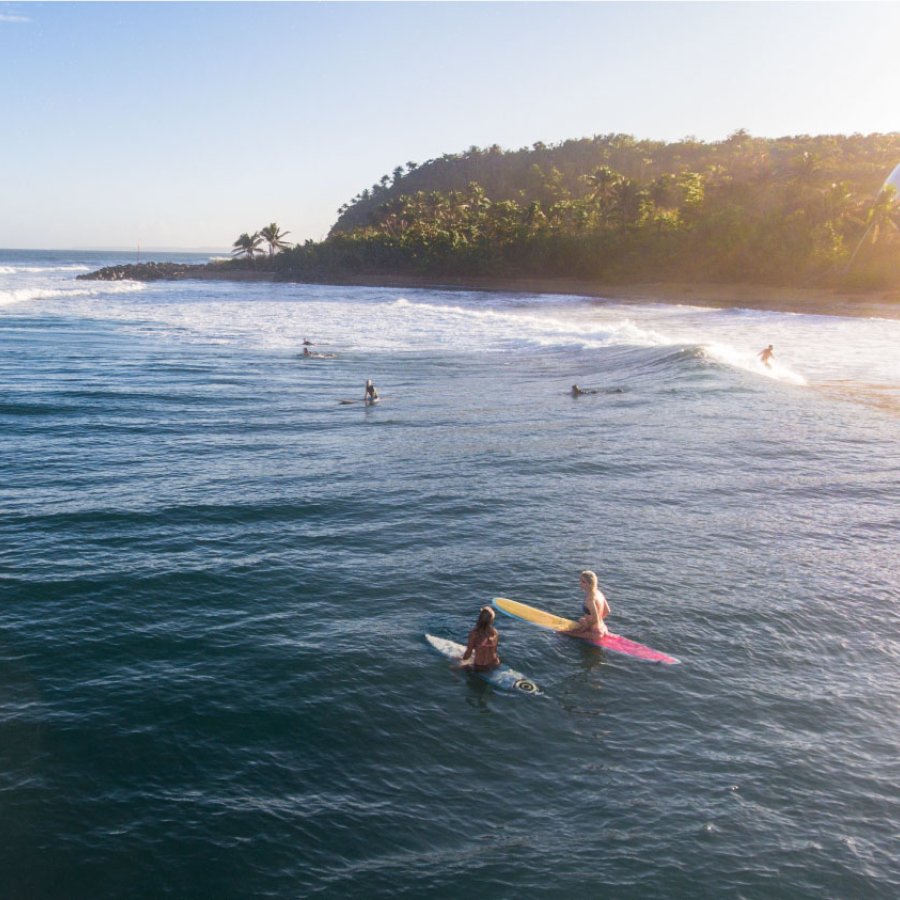 Surfers paddle out to catch a wave at Domes Beach in Rincon, Puerto Rico.
