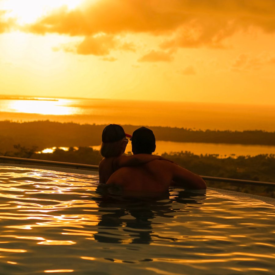 A couple views a sunset from an infinity pool in Puerto Rico.