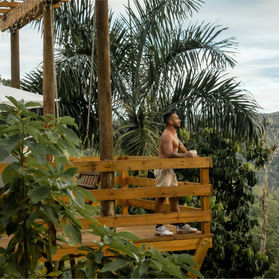  Un hombre se encuentra en una plataforma de madera con vistas a las Montañas Centrales en un alquiler vacacional en Puerto Rico.