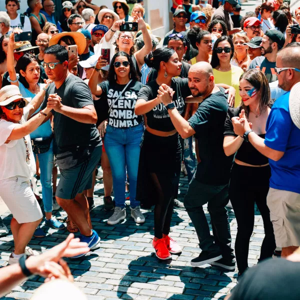 Multitud bailando salsa en las calles del Viejo San Juan, una de las mejores cosas que hacer en Puerto Rico para vivir su cultura.