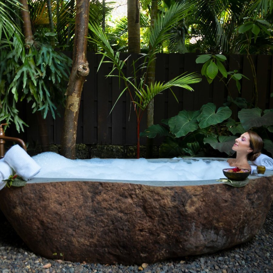 A woman relaxes in an outdoor stone bathtub at Spa Botanico in Puerto Rico.
